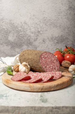 Biberli salam ve kesme tahtasında dilimler. Gri arka planda biberli İtalyan salamı. Kapat.