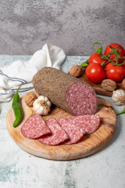 Biberli salam ve kesme tahtasında dilimler. Gri arka planda biberli İtalyan salamı