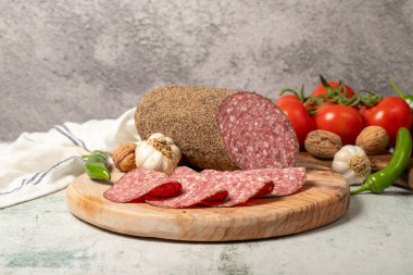 Biberli salam ve kesme tahtasında dilimler. Gri arka planda biberli İtalyan salamı