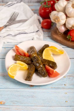 Zeytin yağıyla doldurulmuş üzüm yaprakları. Aperatif yemekler. Doldurulmuş yaprak ve mavi ahşap arka planda et. yerel adı yaprak sarma