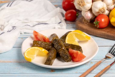 Zeytin yağıyla doldurulmuş üzüm yaprakları. Aperatif yemekler. Doldurulmuş yaprak ve mavi ahşap arka planda et. yerel adı yaprak sarma