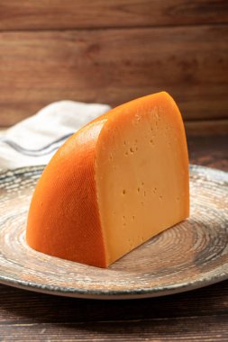 Mimolette peyniri. Süt ürünleri. Tabakta Mimolette peyniri dilimleri. Kapat.