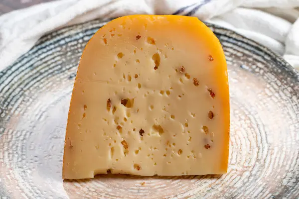 Gouda herb cheese. Dairy products. Slices of gouda cheese with fenugreek on a plate