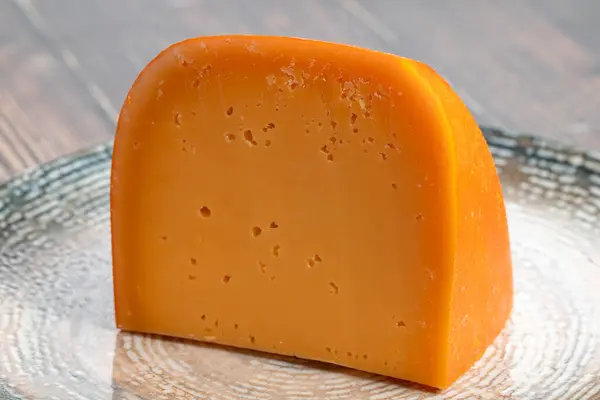 Mimolette cheese. Dairy products. Slices of Mimolette cheese on a plate. Close up