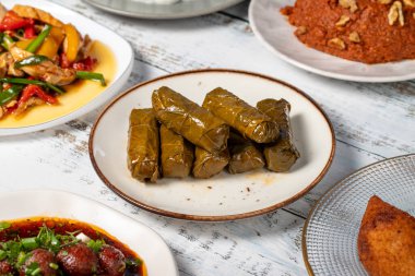 Aperatif çeşitleri. Geleneksel Türk ve Arap lezzetleri. Beyaz ahşap arka planda çeşitli meze tatları. Dolma, Muhammara, zeytinyağlı enginar, kibbe, tavuk salatası, patlıcan salatası