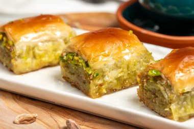 Kırsal masada Türk kahvesi, ramazan ya da bayram tatlıları konsepti olan şam fıstıklı baklava. Orta Doğu mutfağı aromalı. Kapat.