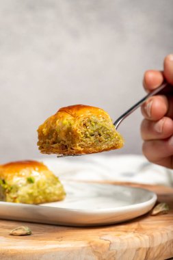 Türk baklavası. Akdeniz mutfağı aromalı. Çatalla fıstıklı baklava tutuyor. Kapat.