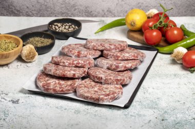 Hamburger Patty. Kasap ürünleri. Arkaplanda jelatinli çiğ hamburger köfteleri.