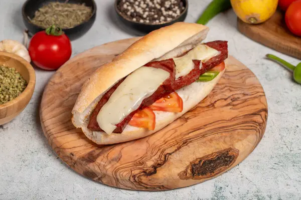 Turkish bread sandwich with kashar sausage on the presentation board. Sausage in bread prepared with tomatoes, peppers and meatballs. Local name ekmek arasi sucuk