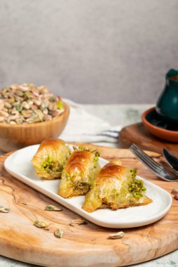 Fıstıklı sobiyet baklava. Türk ve Arap mutfağı lezzetleri. ahşap bir sunum tabağında pıhtılaşmış krema ve fıstık ile sobiyet baklava