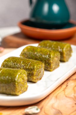 Ahşap arka planda fıstıklı baklava. Türk mutfağı lezzetleri. Ramazan tatlısı. Yerel adı sarma veya durum baklava