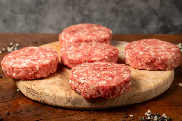 Raw hamburger patty. Butcher products. Fresh hamburger patty meat on dark background. Close up
