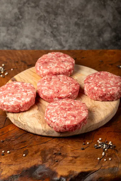 Raw hamburger patty. Butcher products. Fresh hamburger patty meat on dark background