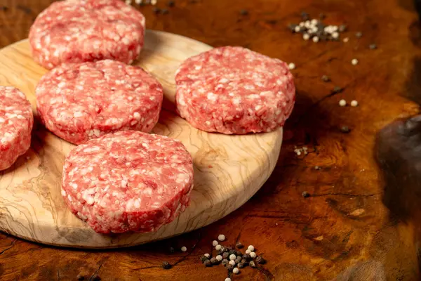Raw hamburger patty. Butcher products. Fresh hamburger patty meat on dark background. Space for text