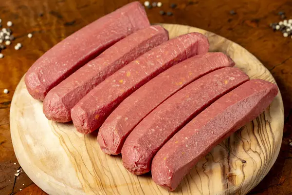 Raw sausage. Butcher products. Sausages made from uncooked beef on a dark background. Close up