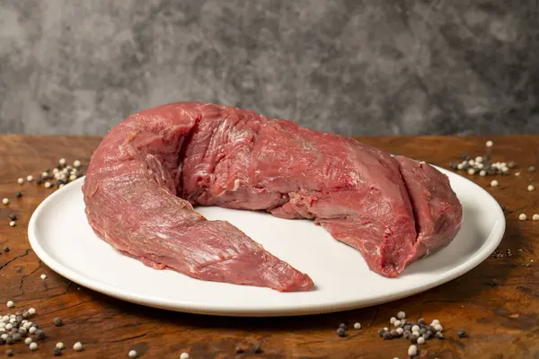 Raw Beef Tenderloin. Butcher products. Uncooked beef tenderloin on a dark background. Close up