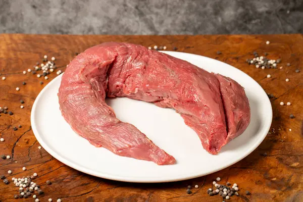 Raw Beef Tenderloin. Butcher products. Uncooked beef tenderloin on a dark background.