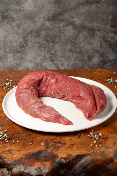 Raw Beef Tenderloin. Butcher products. Uncooked beef tenderloin on a dark background. Close up