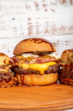 Çedar peynirli hamburgerler ve ahşap arka planda özel bir sos. Kapat.