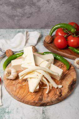 İp peyniri. Tahta servis tahtasındaki tel peynir taneleri.