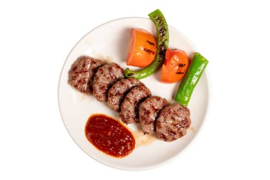 Beyaz arka planda ızgara köfteler. Domates, biber, aperatif ve özel sosla. Tabakta Türk köftesi. Üst görünüm