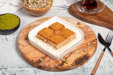 Bisküvi ve sütle birlikte baklava. Tahta servis tahtasının üzerinde bisküvi olan soğuk baklava. Türk mutfağının ünlü yemekleri
