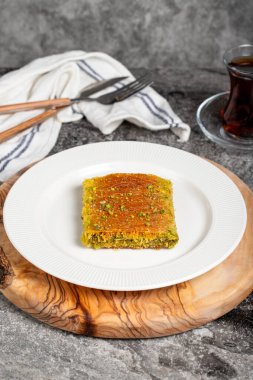 Wicker kadayif. Traditional Turkish cuisine desserts. Wicker kadayif with pistachios on a wooden serving board clipart
