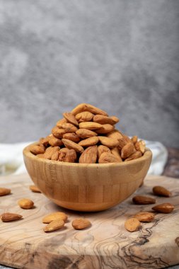 Ahşap arka planda badem. Kavrulmuş badem bir kasede. Kapat.