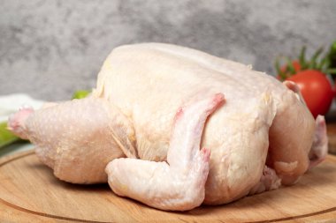 Tam tavuk. Çiğ tavuk, ahşap servis tahtasına soyulmuş. Kapat.