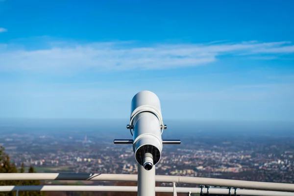 stock image Telescope placed on viewing platform on Szyndzielnia Mountain in Bielsko-Biala, Poland. Railing of observation tower deck. Cityscape in the background. Blurred horizon. 