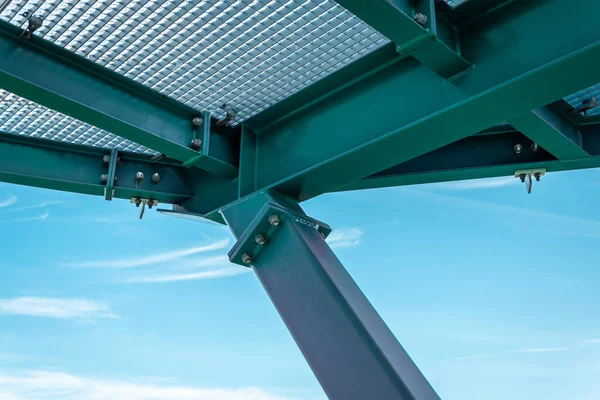 stock image Construction on an observation's tower deck made from green metal bars and I-beams bolted together. Deck made of perforated vema lattice. Blue, cloudy sky in the backgroud. 