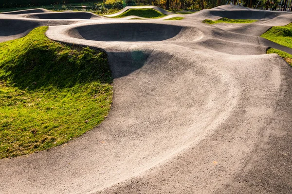 stock image Blurred biker riding on an asphalt pump track surrounded by nature on a sunny day. Extreme sport and great way to spend free time. 