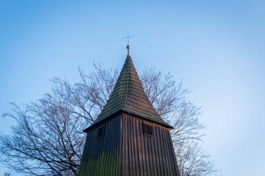 Katolik, Silezya, Polonya 'daki Aziz Mikail Kilisesi' nin çan kulesinde metal haç. XVI. Yüzyılın başından beri tahta tapınak. Arkaplanda yapraksız ağaç. 
