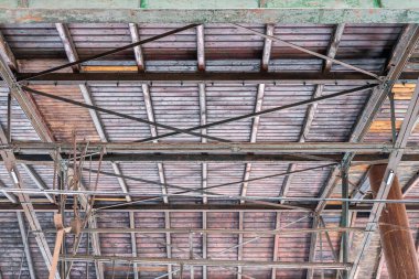 Gable roof truss of a large, vintage factory hall. Roofing construction (sheathing) made of wooden planks. Industrial interior.