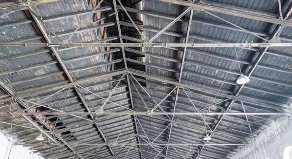 Gable roof truss of a large, vintage factory hall. Roofing construction (sheathing) made of wooden planks. Industrial interior.