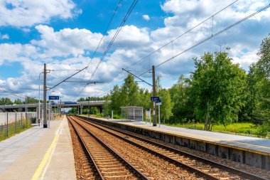Küçük bir tren istasyonu. Arka planda araba köprüsü ve araba nakliyesi. Güneşli bir gün