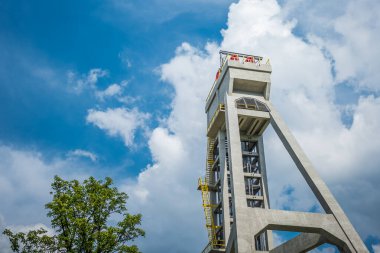 The tower of the former mine shaft against the blue sky and in the company of a tree. Currently an observation tower. Shaft President, Chorzow, Poland clipart