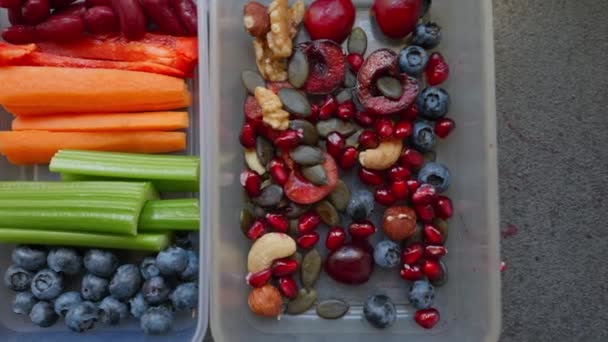 カラフルな野菜や果物でいっぱいの健康食品とボックス ナッツ ブルーベリー ヨーグルト ザクロ バナナ グルテンフリーパンケーキ レーズン セロリ ニンジン — ストック動画