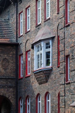 İşçi konutlarındaki bir apartmanın tuğla cephesi. Güzel pencere ayrıntıları. Beyaz pencere çerçeveleri. Pencere kenarında. Tarihi konutlar Katowice Nikiszowiec. Polonya