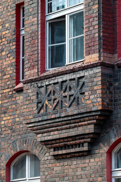 İşçi konutlarındaki bir apartmanın tuğla cephesi. Güzel pencere ayrıntıları. Beyaz pencere çerçeveleri. Pencere kenarında. Tarihi konutlar Katowice Nikiszowiec. Polonya