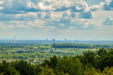 Panorama, manzara. Yeşillik ön planda. Uzak dağların arka planına karşı Katowice şehri gökdelenleri.