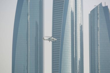 Abu Dabi. BAE - 18 Mart 2024: Abu Dabi şehrindeki gökdelenlerin üzerinde uçan helikopter