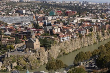 Tiflis, nehir kenarındaki eşsiz mimarisini ve canlı şehir yaşamını sergiliyor. Güneş, modern şehir gelişmelerinin bir zeminine karşı tarihi yapıları aydınlatıyor..