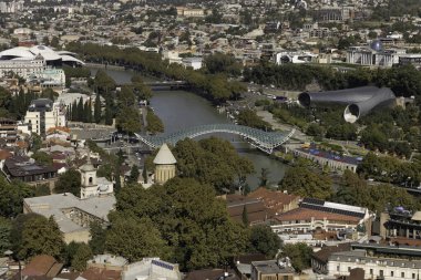 Tiflis 'in şehri saran Kura Nehri' ni gösteren çarpıcı bir hava görüntüsü. Modern yapılar tarihsel mimariyle kusursuz bir şekilde harmanlanarak canlı bir şehir manzarası yaratırlar..