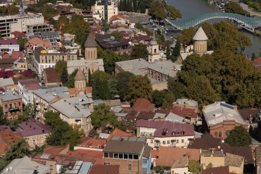 Hava perspektifi, Tiflis 'in yemyeşil ve Mtkvari Nehri ile çevrili tarihi ve modern mimarinin eşsiz bir karışımını sergiliyor. Hareketli şehir hayatı canlı bir atmosfer yaratır..