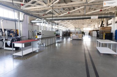 Geniş bir imalat tesisinde, gelişmiş makineler verimli çalışma alanlarıyla düzgünce düzenlenir. Çalışanlar, üretkenliğe olanak sağlayan temiz ve iyi aydınlatılmış bir ortamda çalışırlar..