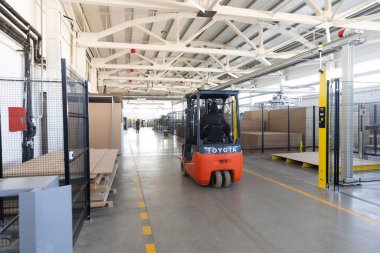 Uçsuz bucaksız bir endüstriyel depodan forklift taşıma malzemeleri. Çevre, raf üniteleri ve güvenlik tedbirlerinin yer aldığı örgütlüdür.