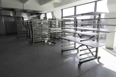 Geniş bir çalışma alanı geniş pencerelere karşı sıralanmış birkaç paslanmaz çelik tabloya sahiptir. Güneş ışığı, çevrenin minimalist tasarımını vurguluyor..