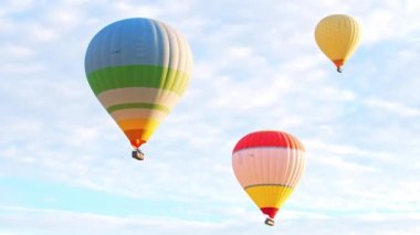 Türkiye 'nin Kapadokya kentinin üzerindeki bulutlu mavi gökyüzü arka planında uçan renkli sıcak hava balonu. Seyahat sırasında ekstrem sporlar ve deneyimler. Yüksek kalite 4k görüntü