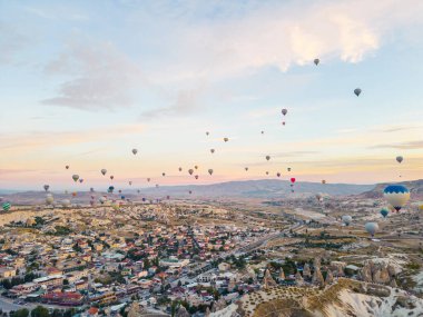 Türkiye 'nin Kapadokya kentinin havadan görünüşü, havada uçuşan çeşitli renkli sıcak hava balonları ve arka planda dağlarla. Yatay çekim. Yüksek kalite fotoğraf